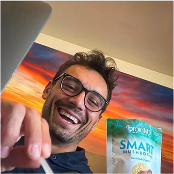 Man holding a package of 'Smart Mushrooms' in front of a colorful painting