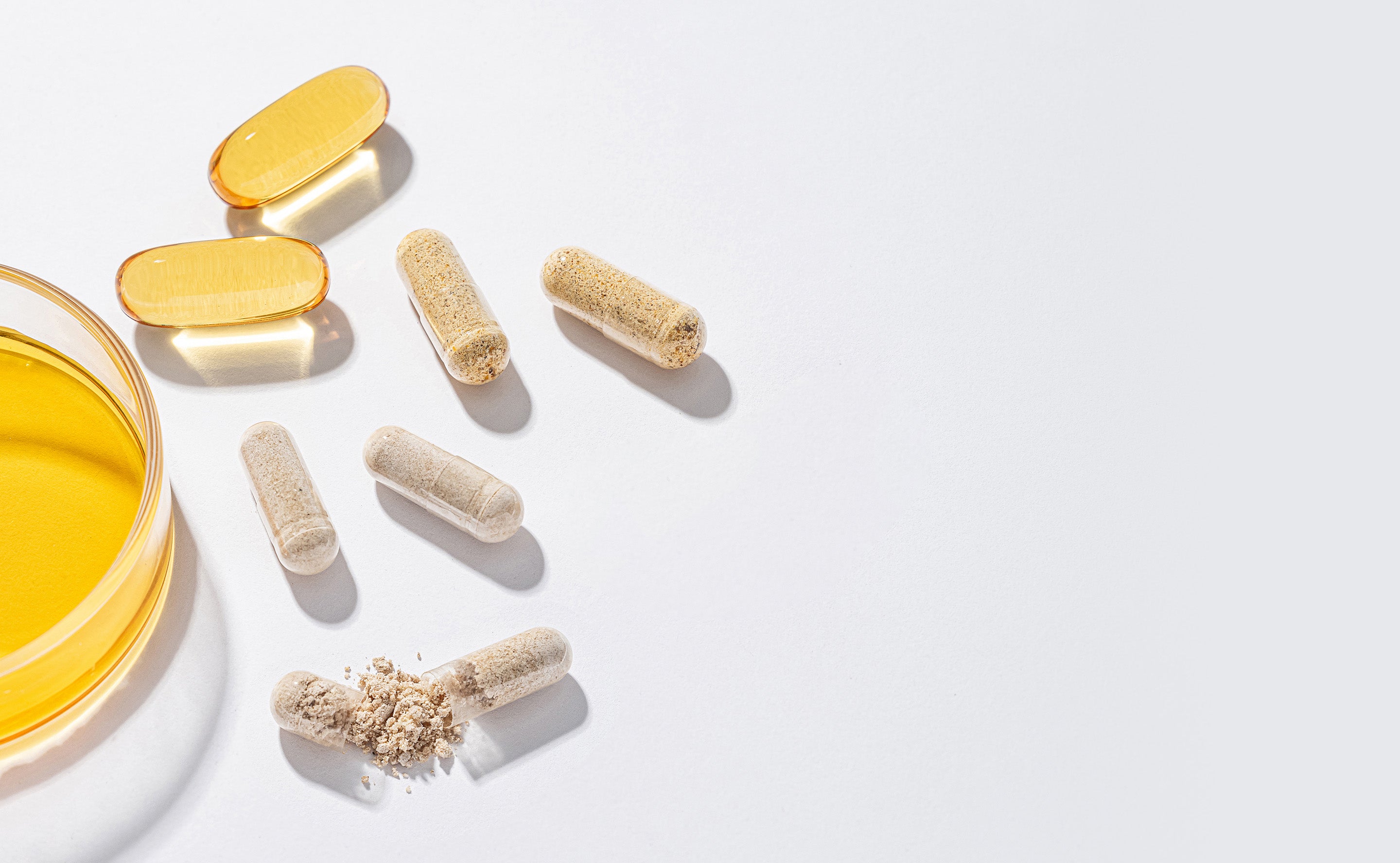 BrainMD Daily Essentials Bundle: capsules, softgels and a glass slide containing yellow oil against a white background