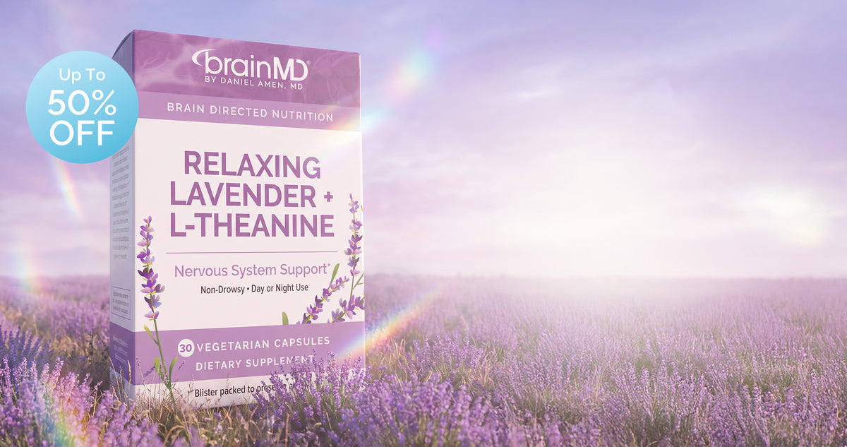 Box of BrainMD Relaxing Lavender + L-Theanine, 30 vegetarian capsules, standing in a blooming lavender field under a soft rainbow with an Up To 50% Off badge.