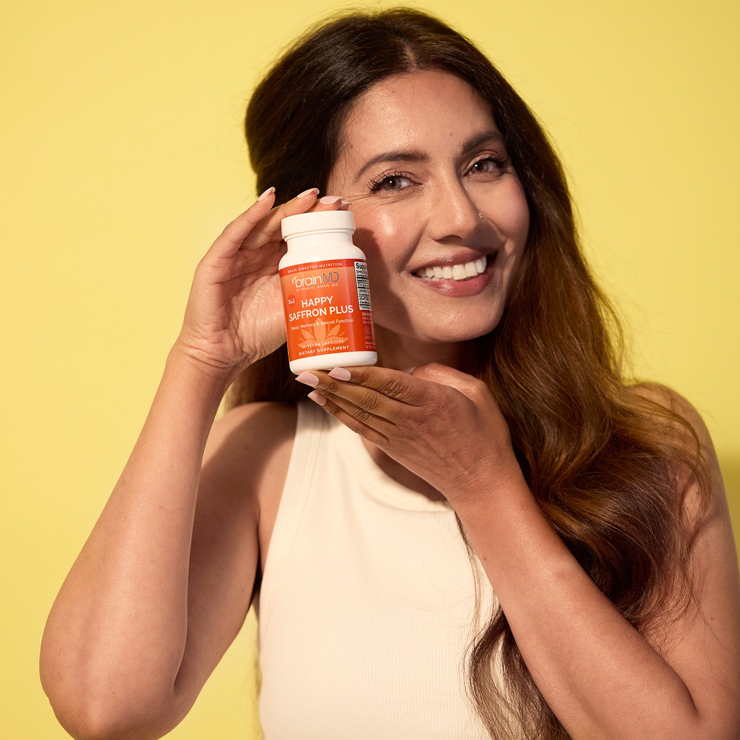 BrainMD 3-in-1 Brain Performance Bundle: woman holding an orange supplement bottle against a yellow background