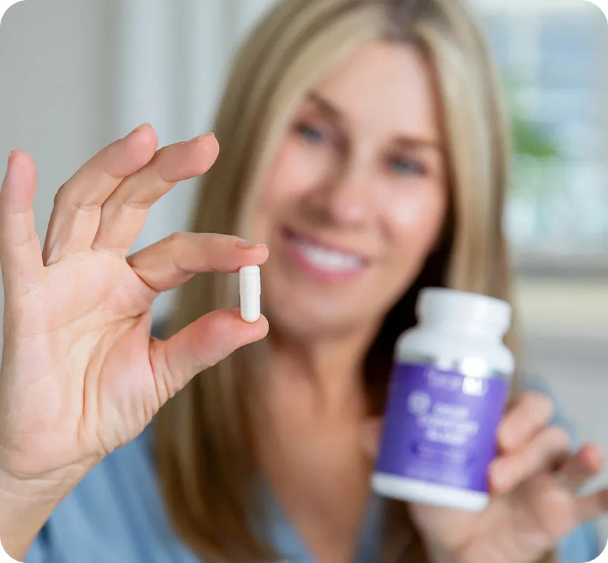 Healthy woman holds a white capsule in her hand.