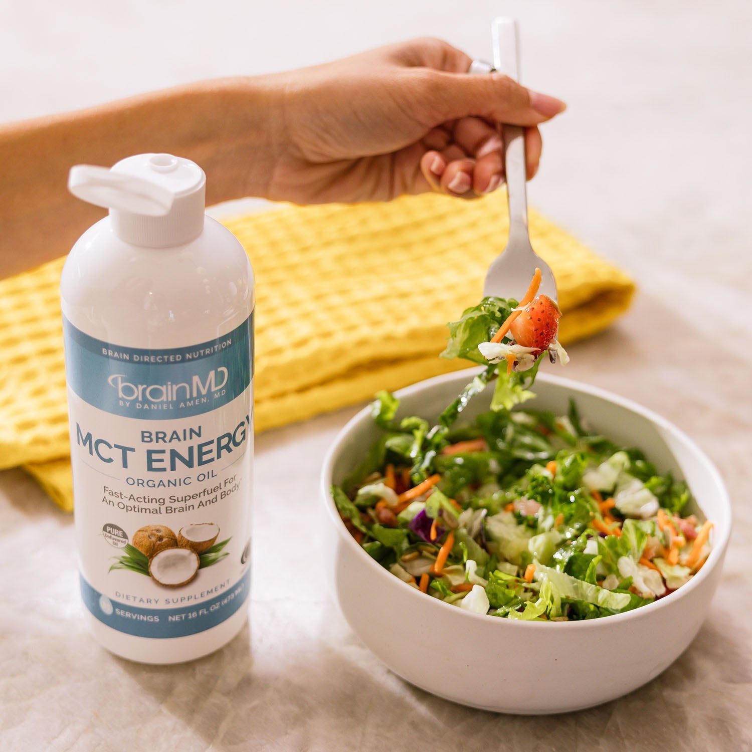BrainMD Brain MCT Energy: blue and white supplement bottle next to a bowl of salad on a marble surface