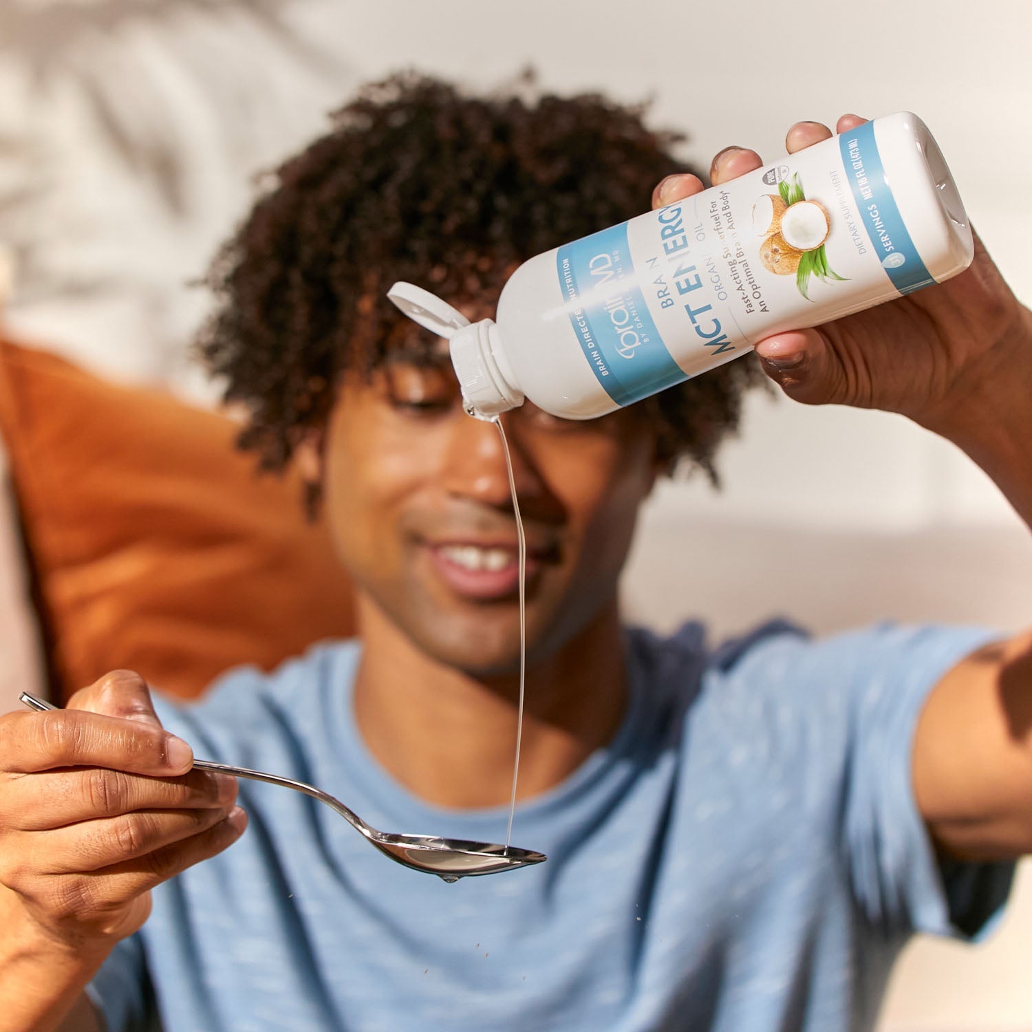 BrainMD Brain MCT Energy: man pours liquid from a blue and white bottle into a spoon