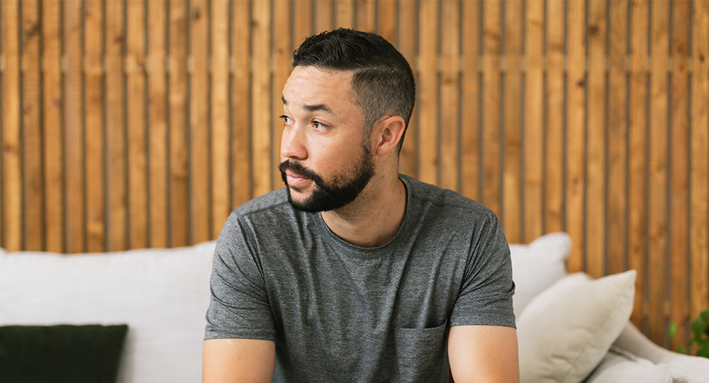 Man sitting on a couch with a wooden wall background