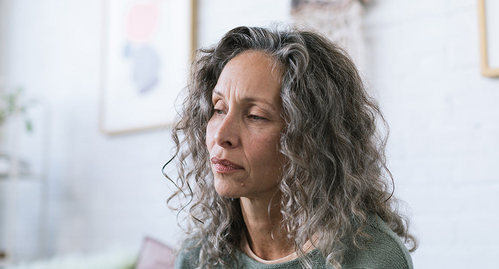Woman with gray hair looking thoughtful indoors