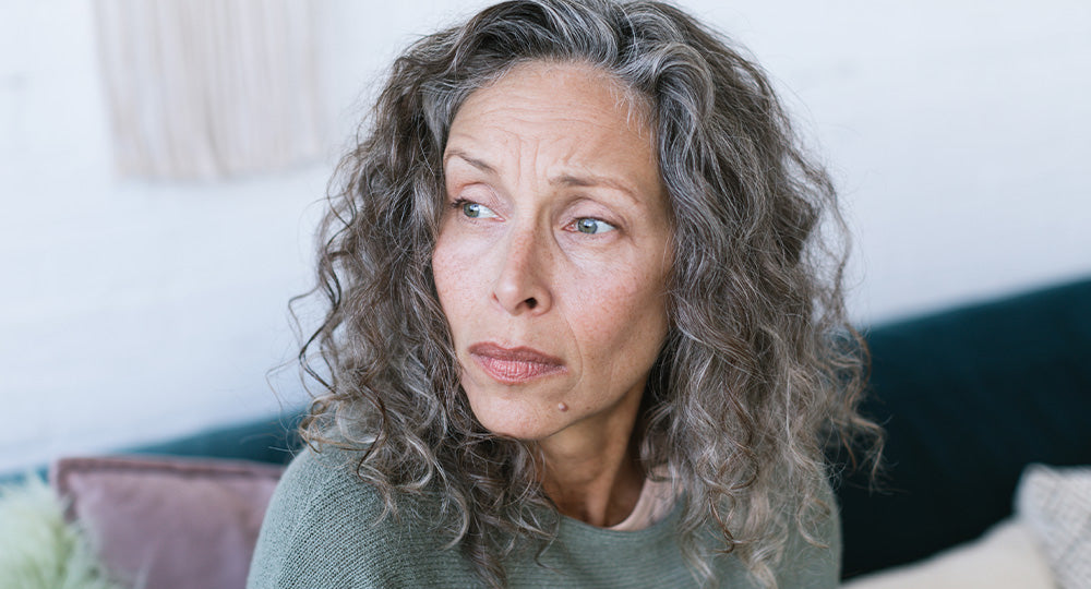 Woman with gray hair sitting on a couch in a living room.