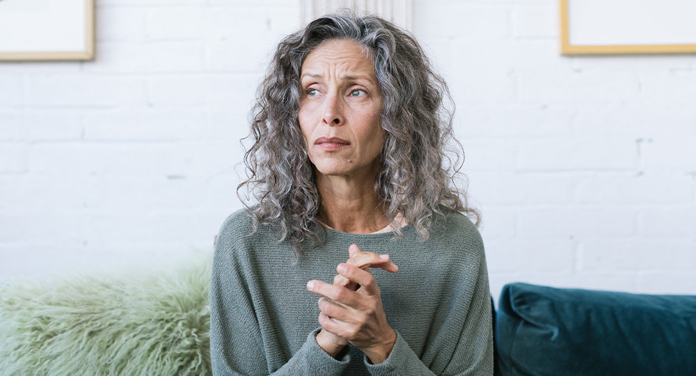 Woman with gray hair sitting on a couch in a living room.
