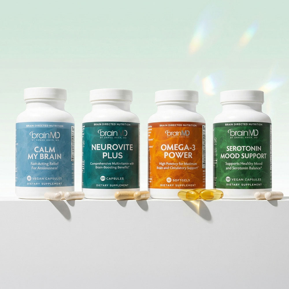 Four supplement bottles in a row with capsules/gelcaps against a light gray background.