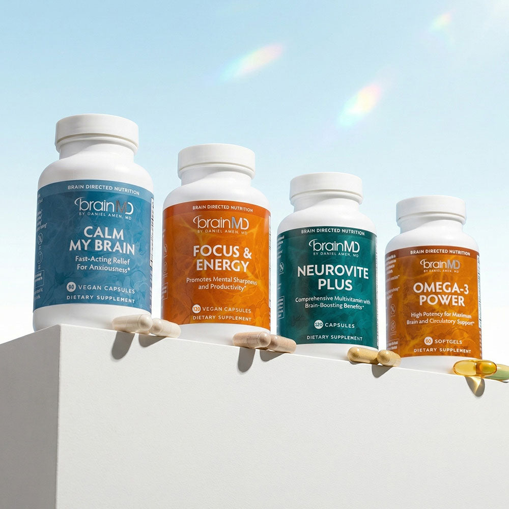 Four supplement bottles in a row with capsules/gelcaps against a light blue background.