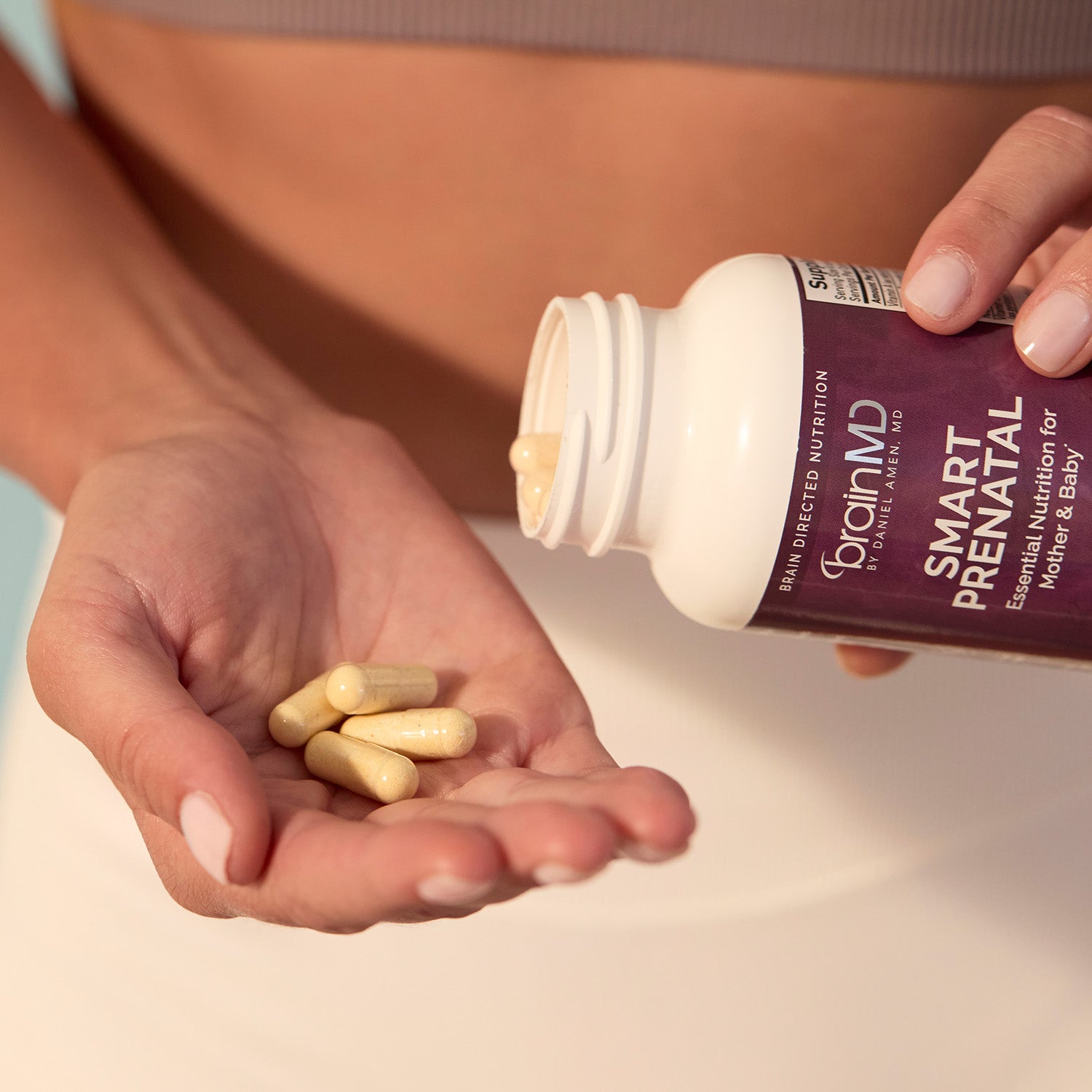 BrainMD Bundle Of Joy: woman pours capsules from a supplement bottle into her palm