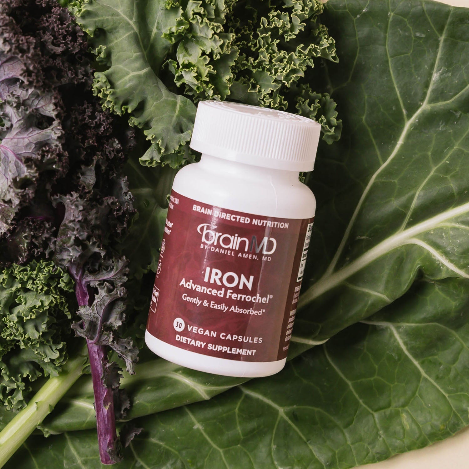 BrainMD Iron: brown supplement bottle resting on top of a bed of leafy greens