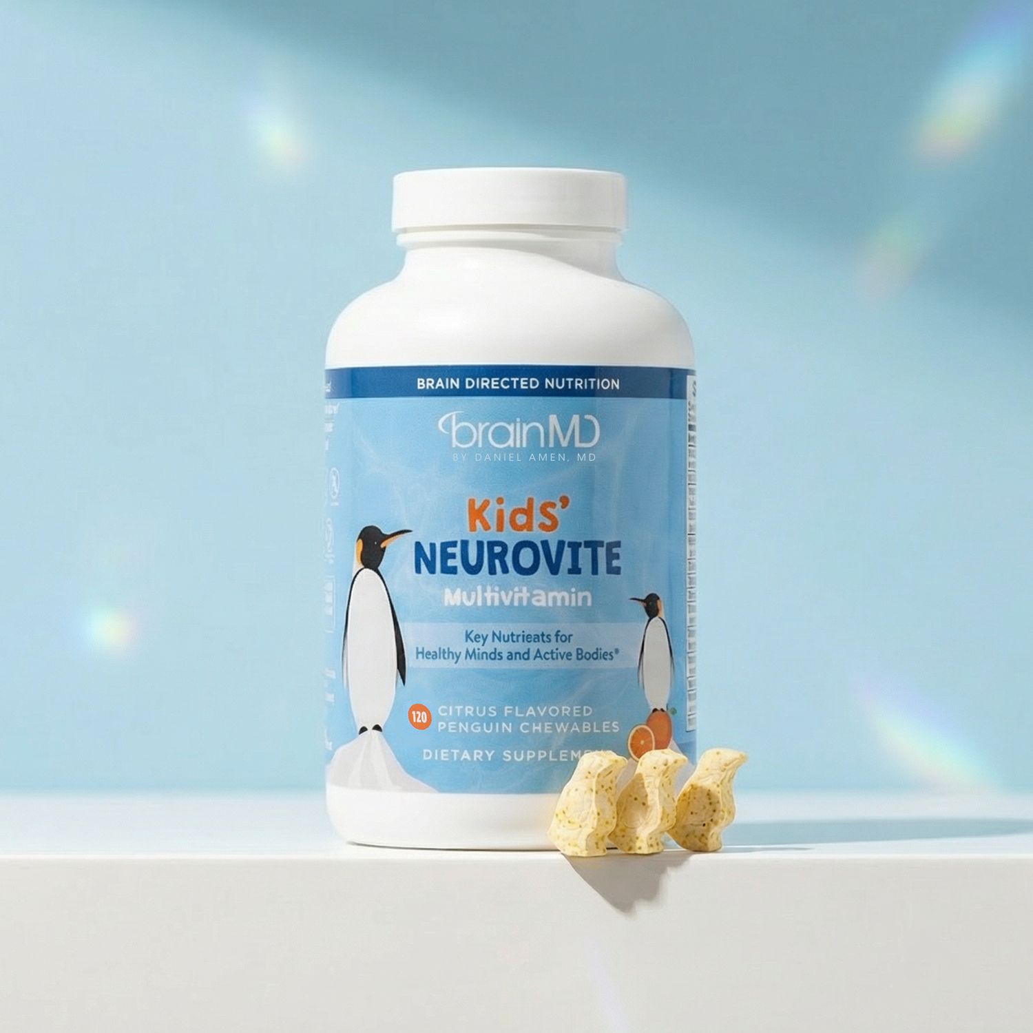 Light blue supplement bottle with penguin-shaped chewables at the base against a powder blue background.