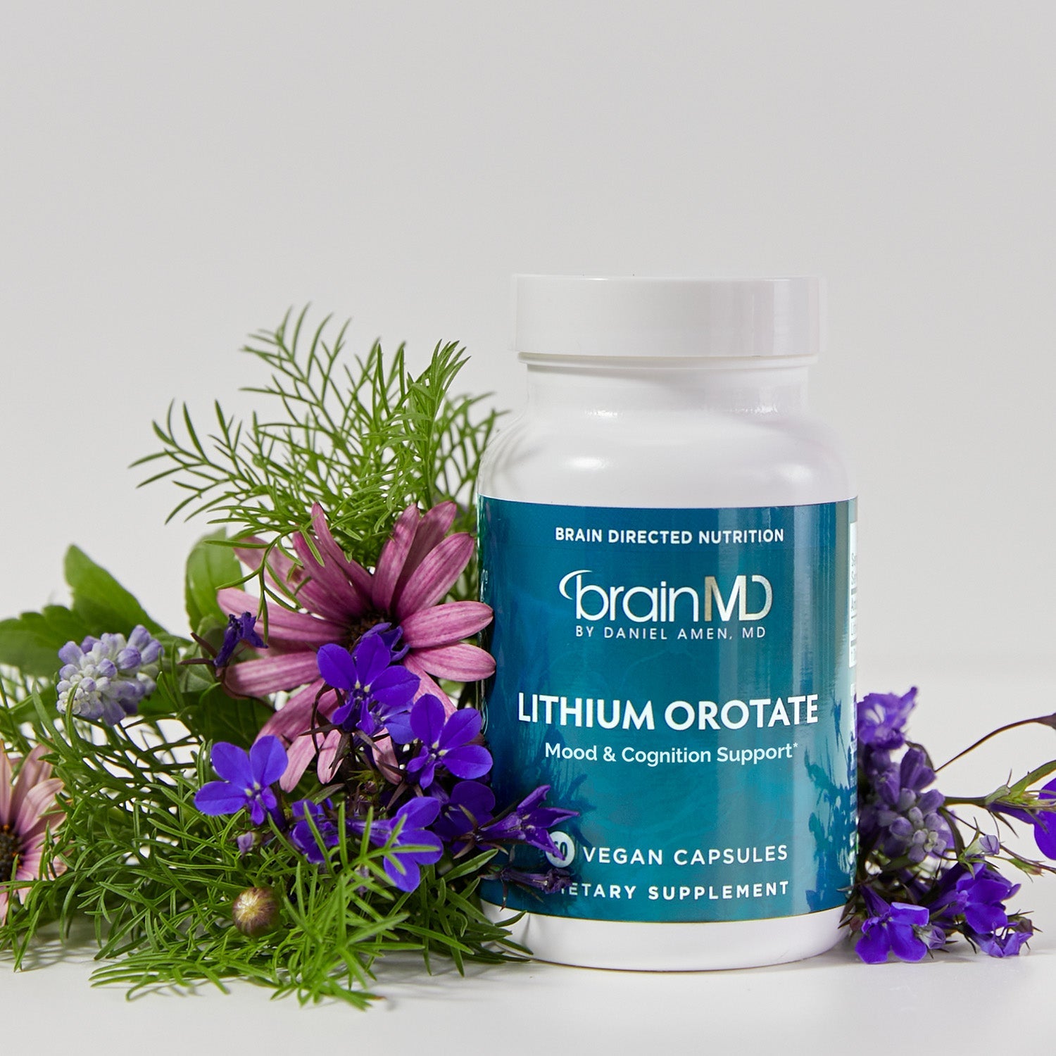 BrainMD Lithium Orotate: bottle of Lithium Orotate with floral arrangement in front of a white background