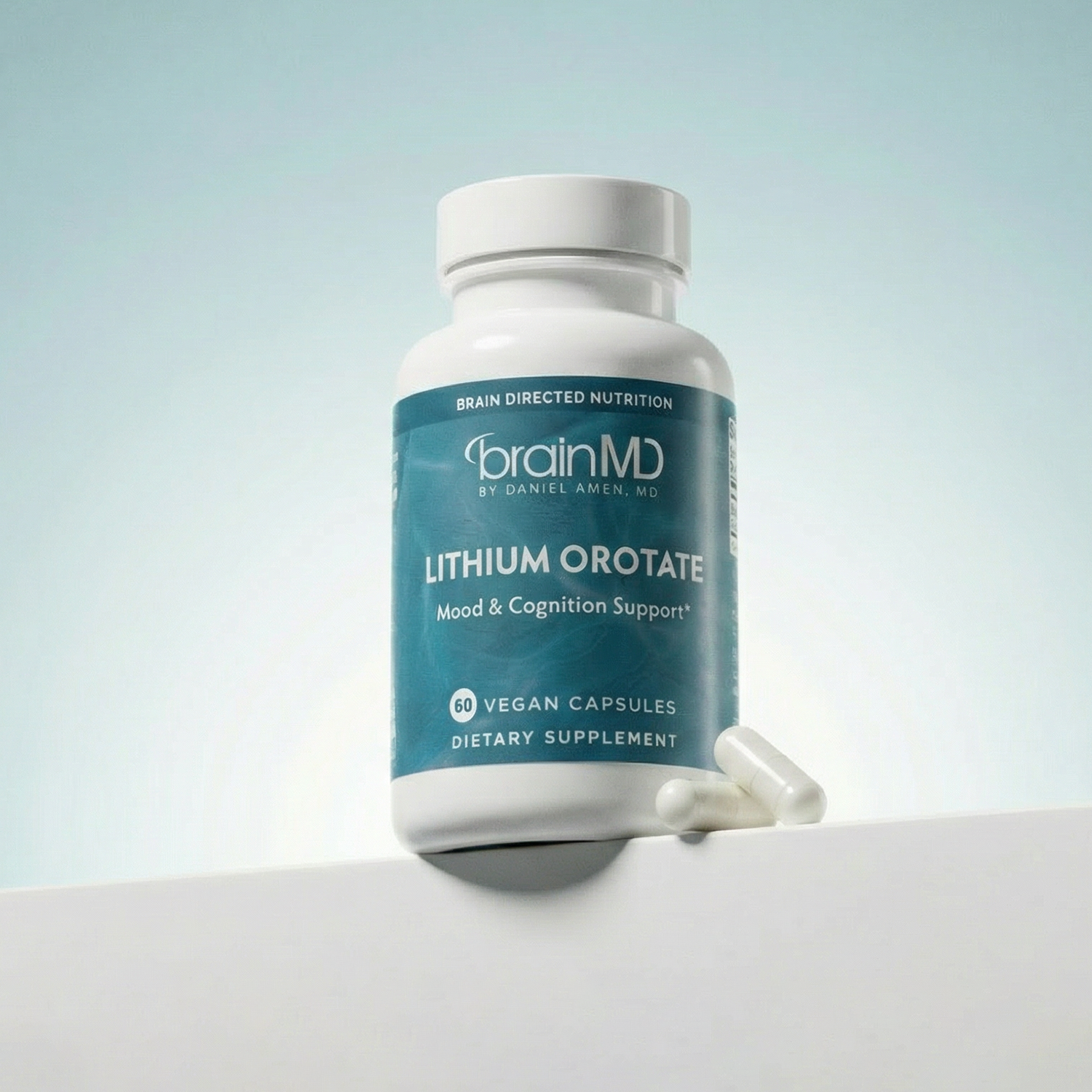 Light blue supplement bottle with white capsules at the base against a powder blue background.