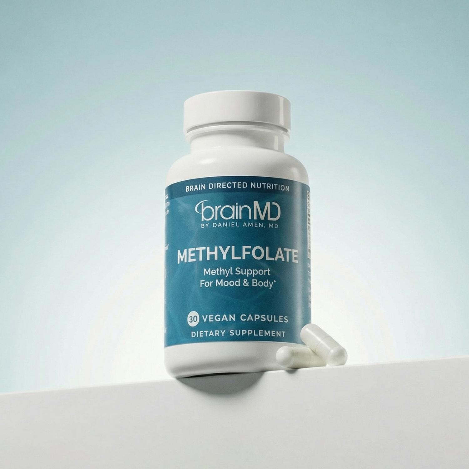 Light blue supplement bottle with white capsules at the base against a powder blue background.