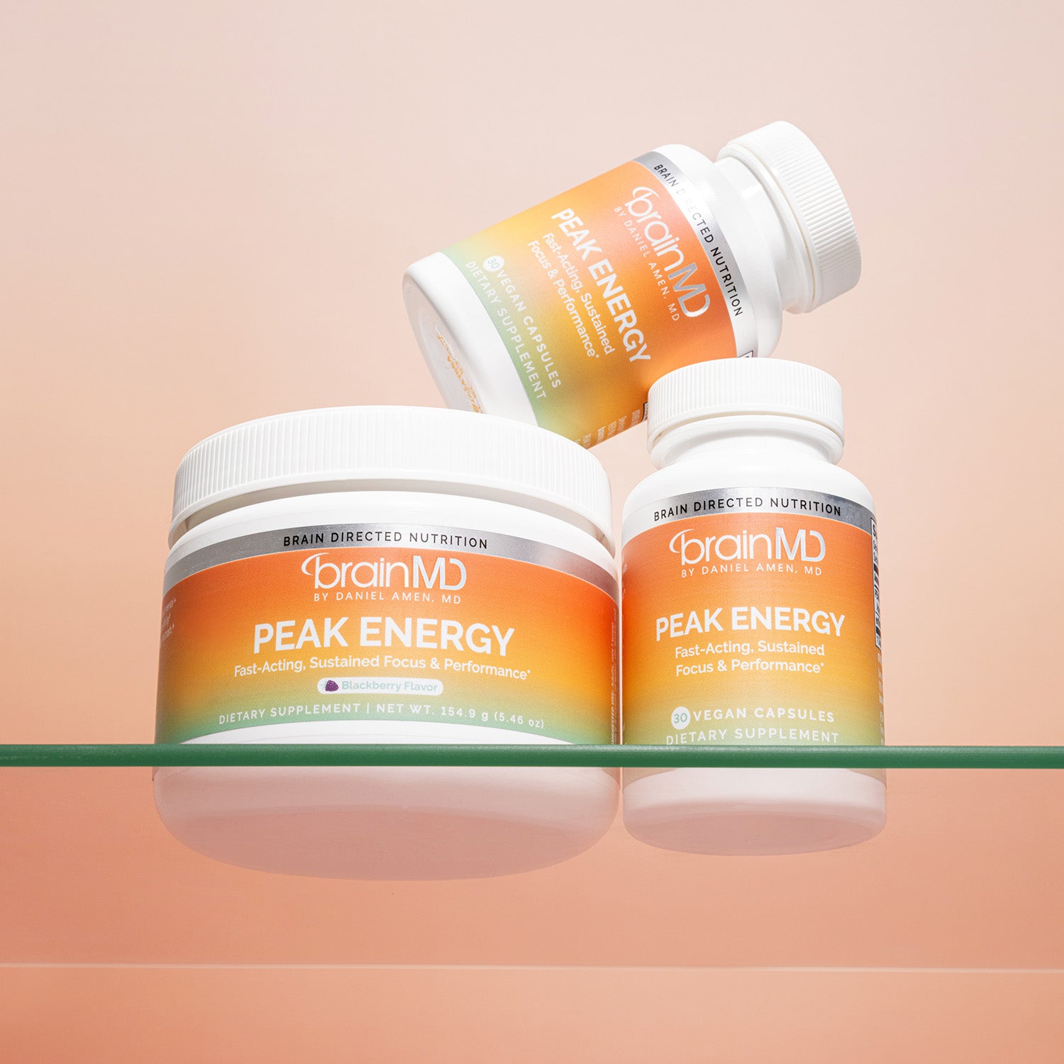 2 bottles and 1 container of Peak Energy against a light peach-colored background.
