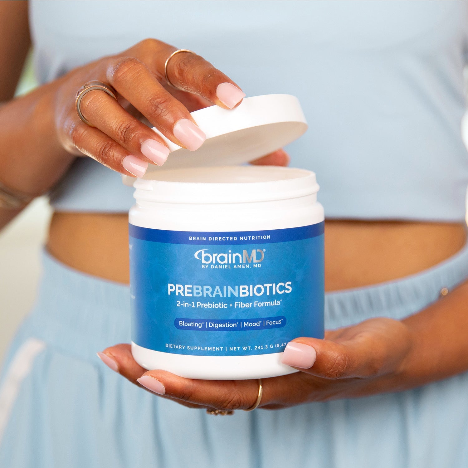 BrainMD PreBrainBiotics: woman holding container of prebiotic + fiber powder