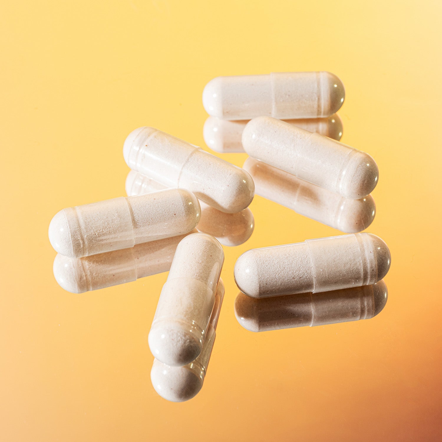 BrainMD Quiet My Mind Sleep: capsules filled with white powder sit atop a mirror with a yellow background