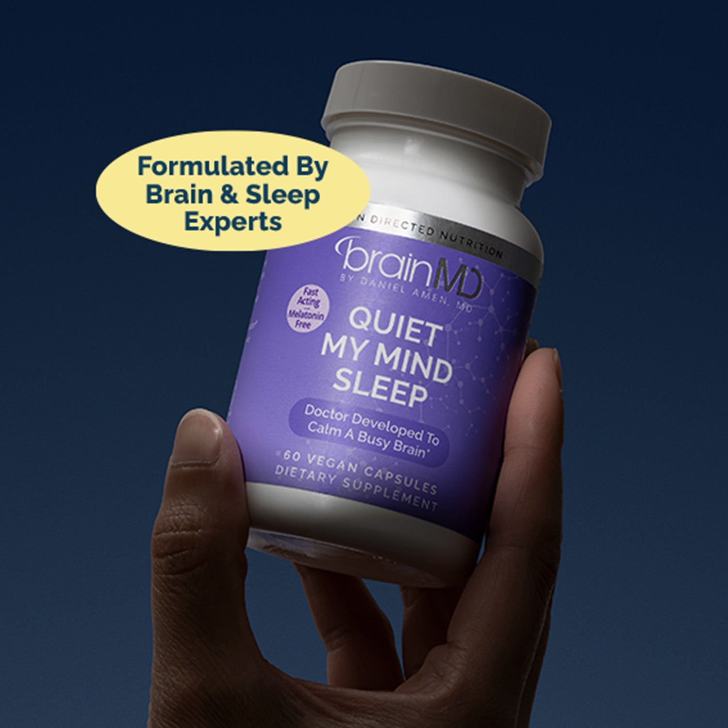 BrainMD Quiet My Mind Sleep: person holds bottle against a dark background, yellow sticker with text overlaps neck of bottle