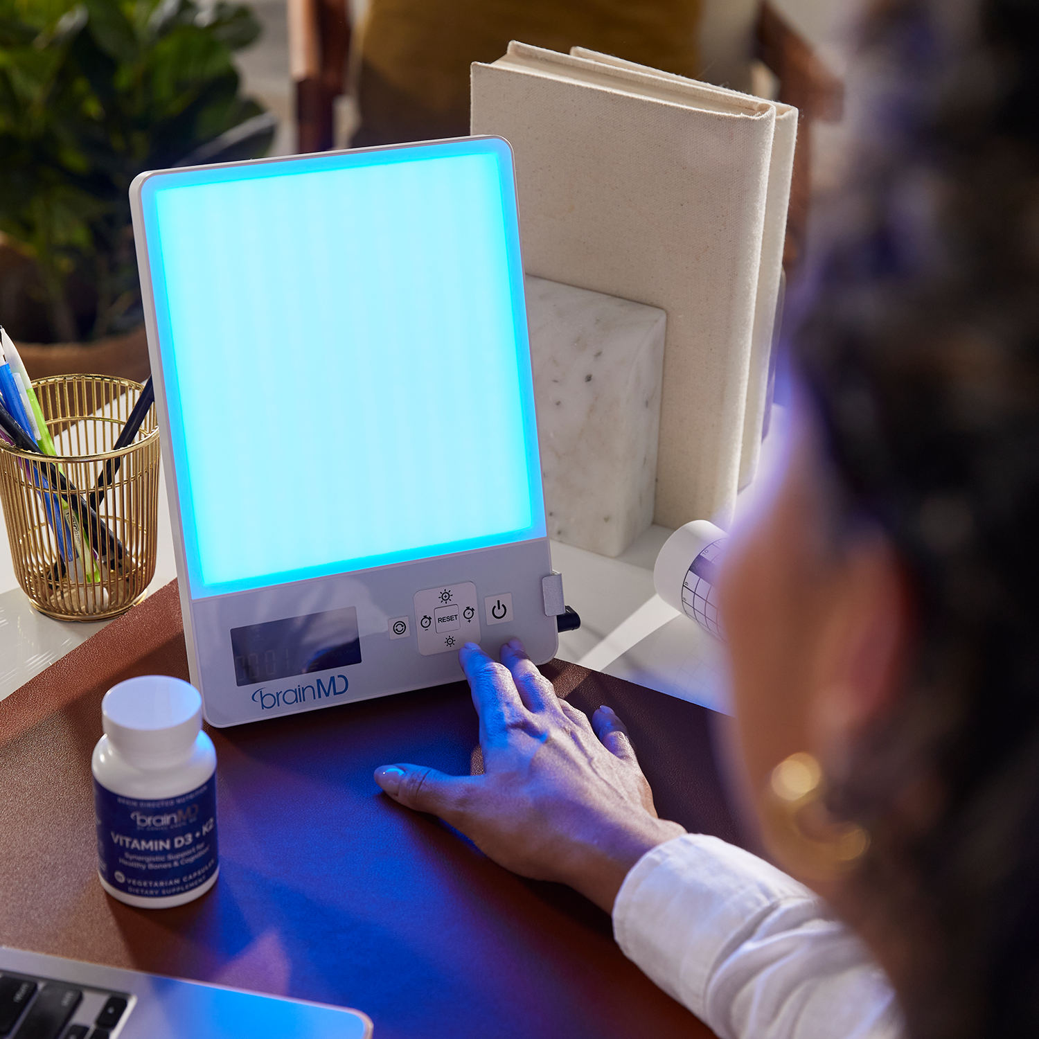 Woman in office basking in the glow of the BRIGHT MINDS Therapy Lamp...front view.