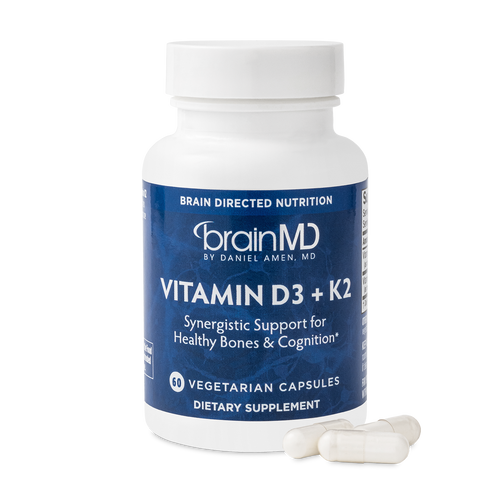 BrainMD Vitamin D3 + K2: image of blue supplement bottle and three off-white capsules at its base with transparent background