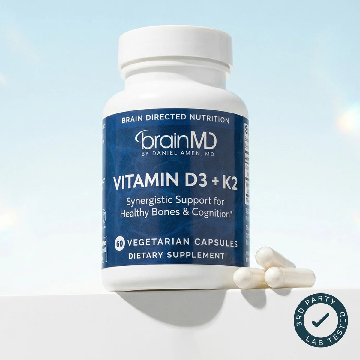 BrainMD Vitamin D3 + K2 bottle of vegetarian capsules on a blue sky background with a third-party tested badge