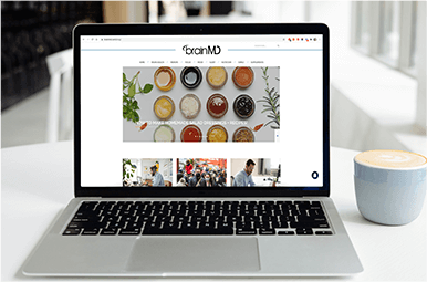 Laptop sitting on a white table with BrainMD's homepage on the screen.