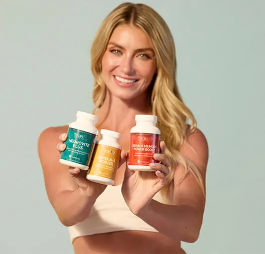Woman holding three supplement bottles against a plain background