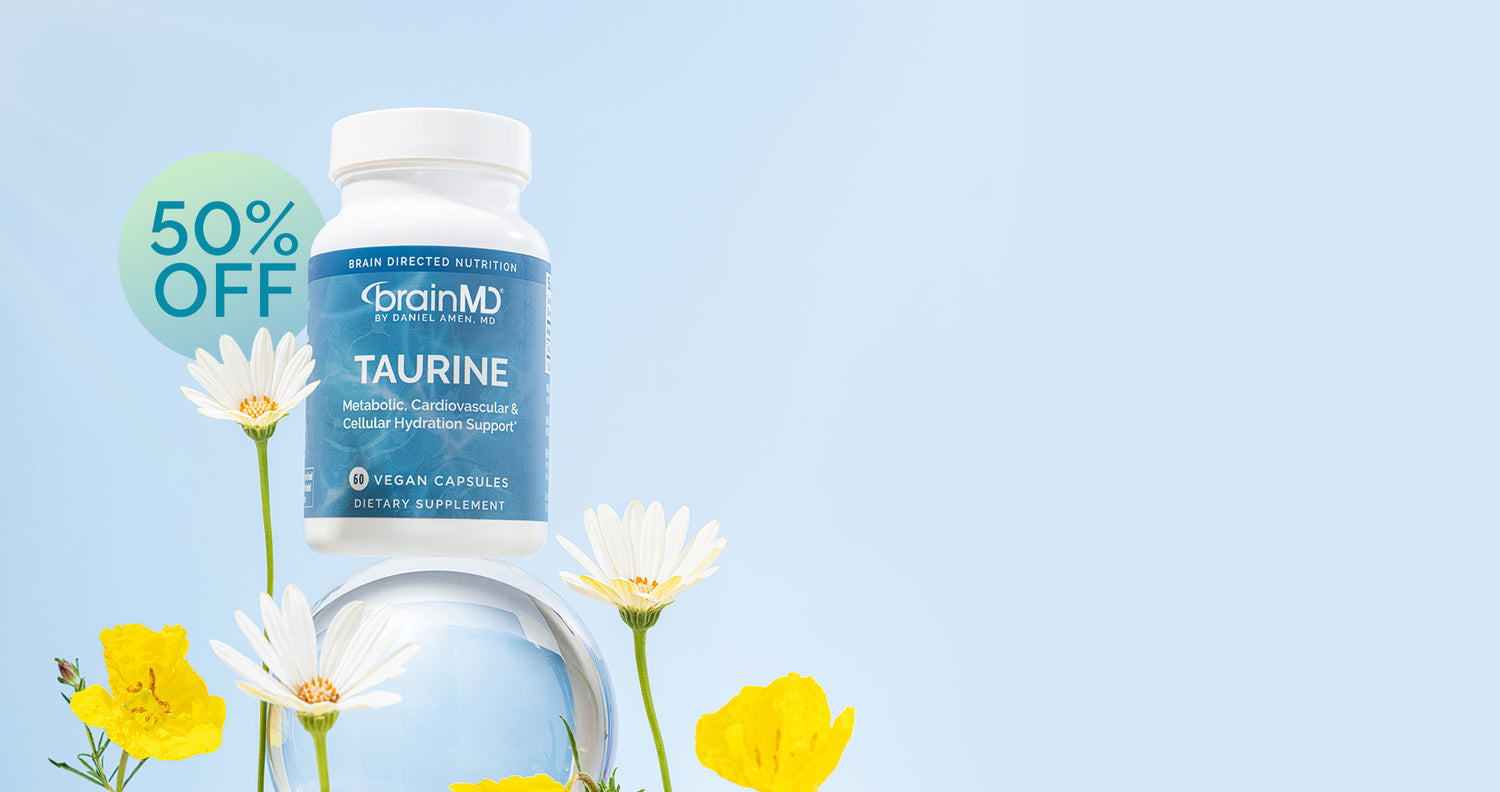 Supplement bottle labeled 'brainMD Taurine' with flowers on a light blue background