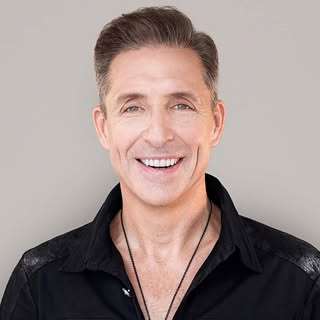 Dave Asprey wearing a black shirt against a gray background