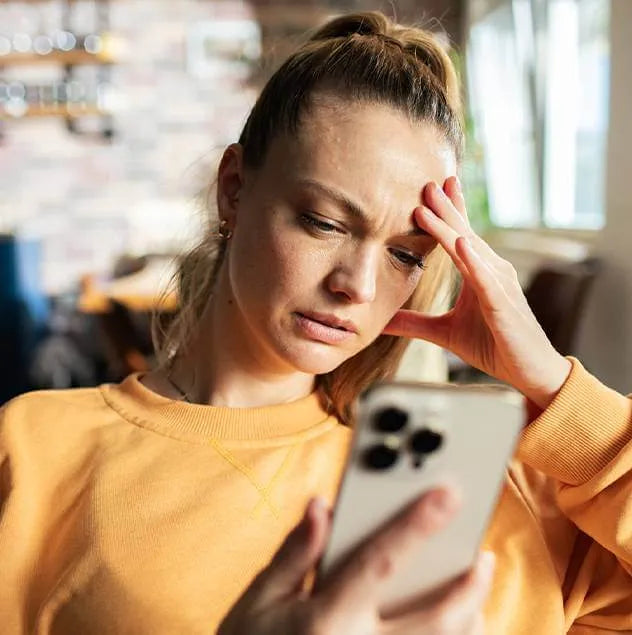 A concerned woman looking at her cellphone, interior setting.