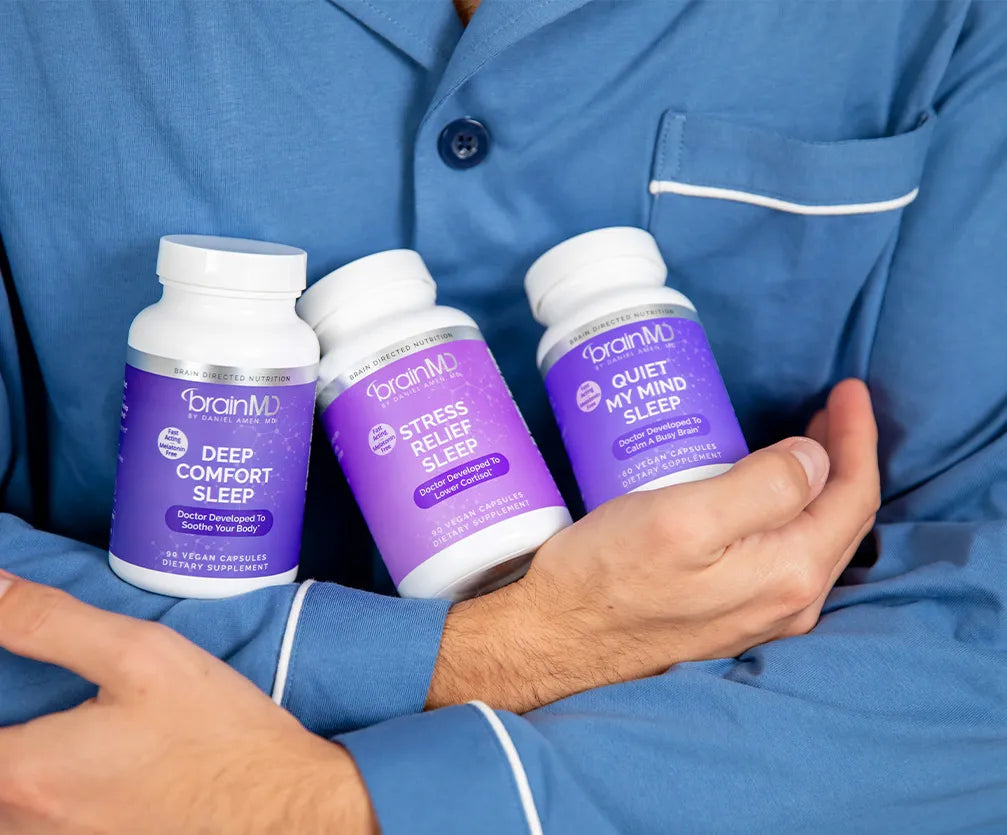 Person cradling 3 sleep supplement bottles.