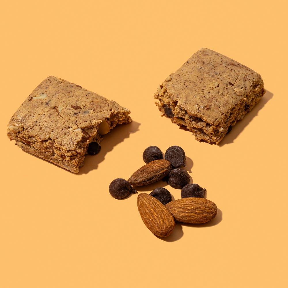 Side-angle closeup of Brain Boost Protein Bar cut open to reveal dense texture and ingredients like almonds, cocoa, and plant protein for brain energy and focus.
