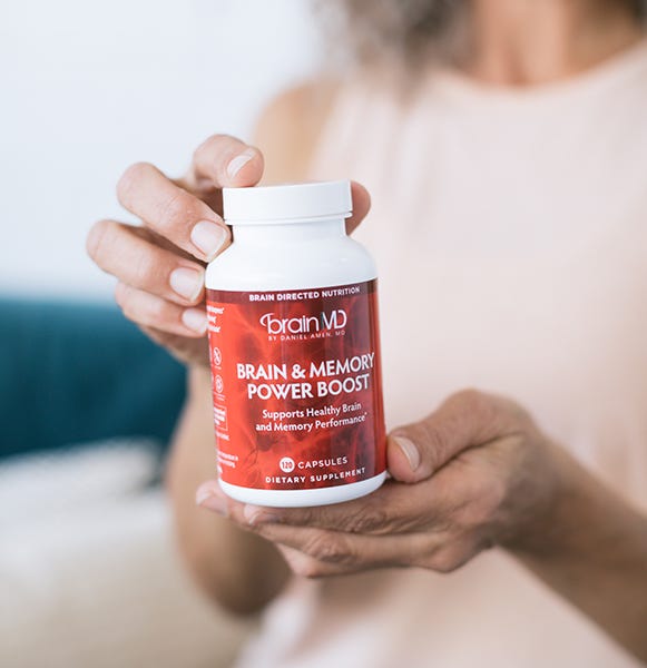 Woman holding Brain & Memory Power Boost supplement for cognitive function and memory support
