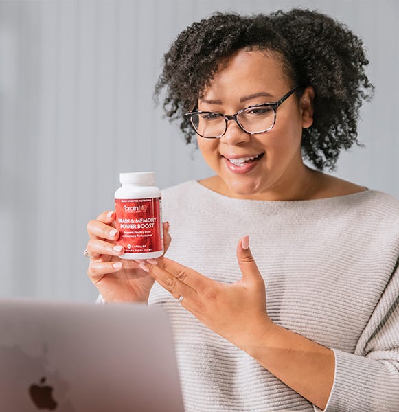 Smiling woman holding Brain & Memory Power Boost supplement, sharing her positive experience via video chat