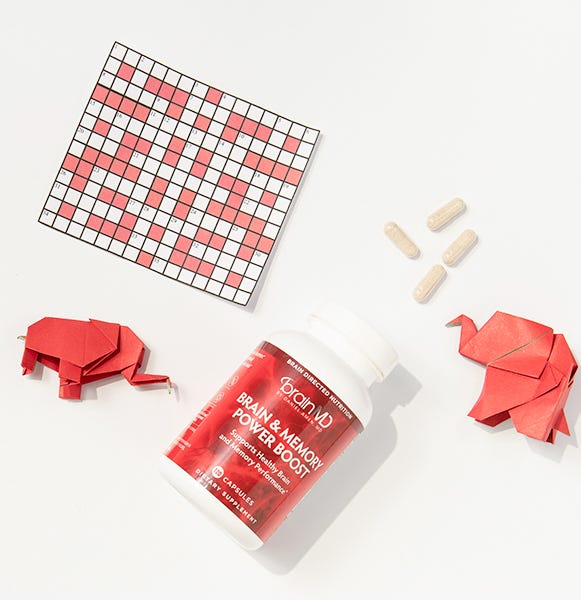Brain & Memory Power Boost bottle with capsules, crossword puzzle, and origami elephants—symbolizing memory, focus, and brain performance